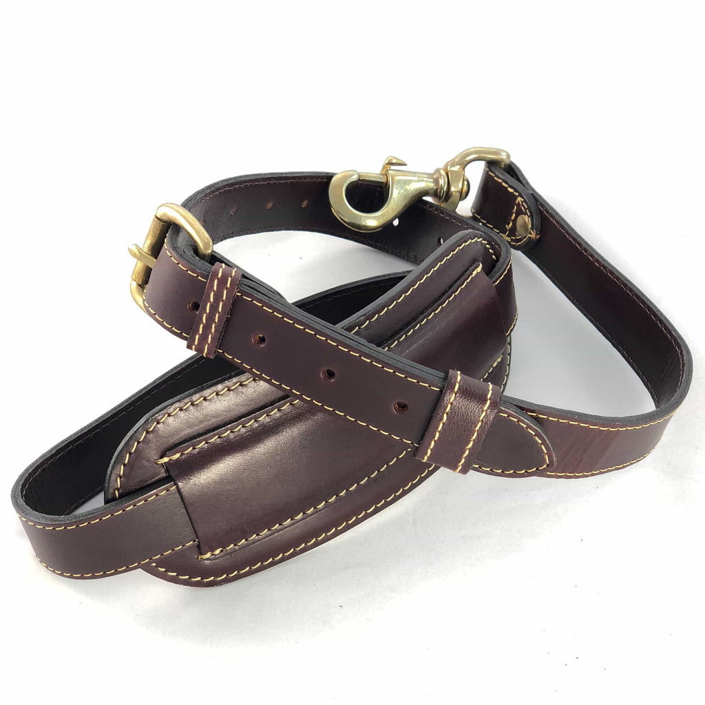 Burgundy leather shoulder strap coiled showing buckle and shoulder pad